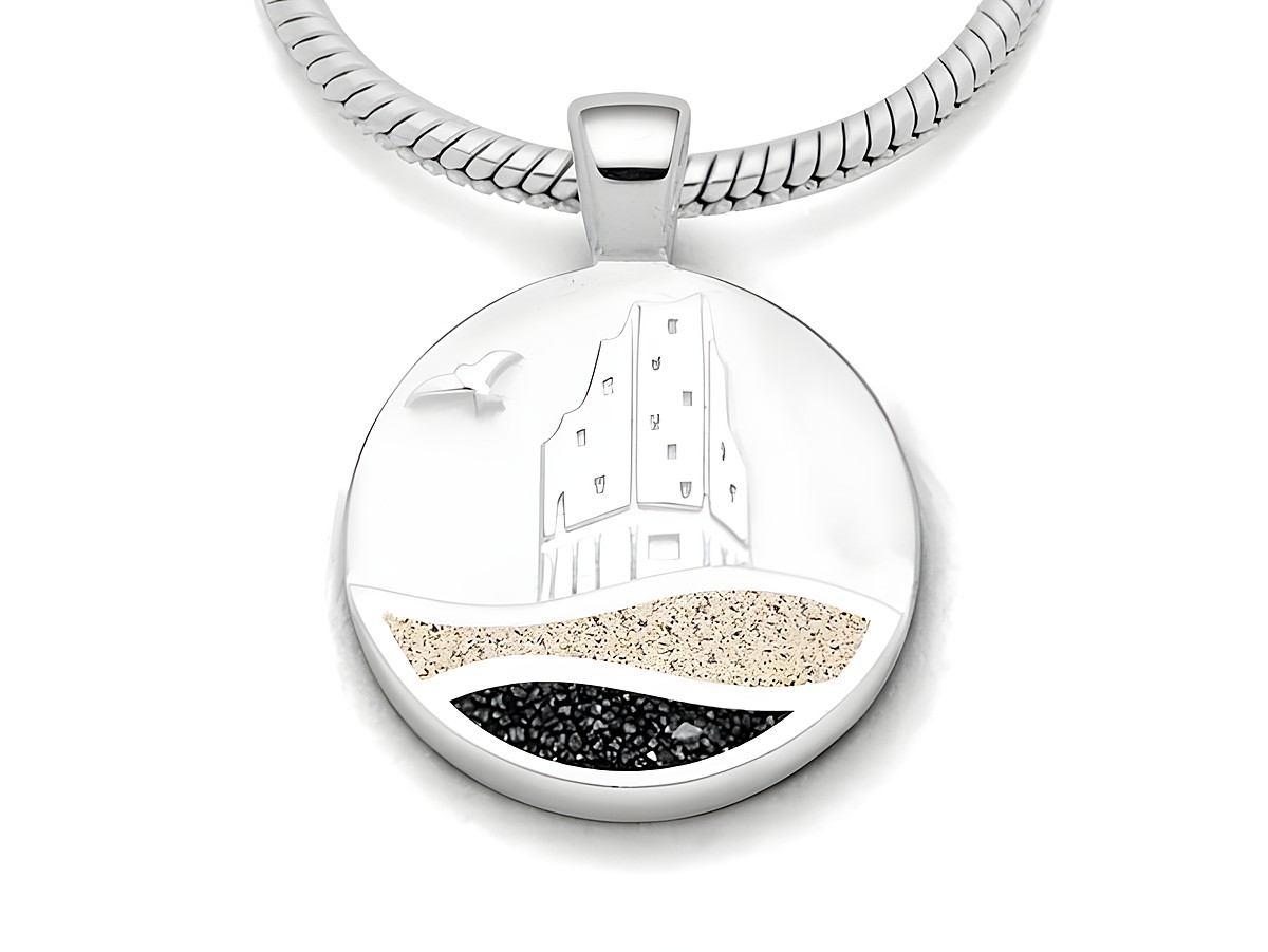 Der Anhänger zeigt eine stilisierte Darstellung eines Gebäudes mit Wellen und Sand in den Farben Strandsand und Lavasand, gefertigt aus rhodiniertem Sterling Silber von DUR.
