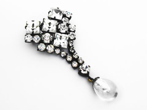 Weiße Strass Damen Brosche im sexy City Look von Juwelier Harnisch, verziert mit funkelnden Strasssteinen und einem elegant hängenden Tropfenanhänger. Ideal für modische Akzente.