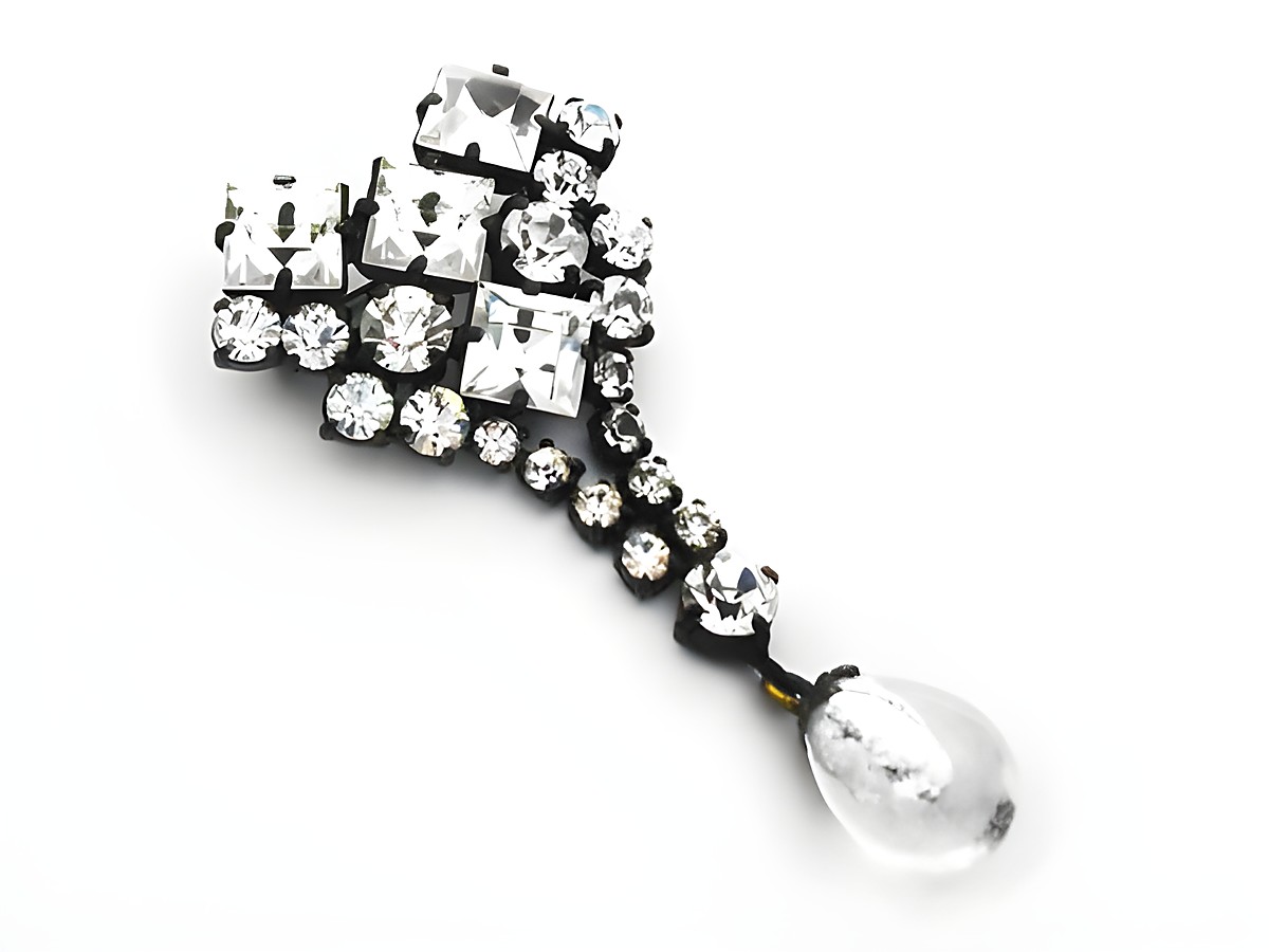 Weiße Strass Damen Brosche im sexy City Look von Juwelier Harnisch, verziert mit funkelnden Strasssteinen und einem elegant hängenden Tropfenanhänger. Ideal für modische Akzente.