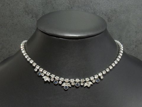 Strass Kette fein in weiß-blau mit einer Länge von 41-44 cm und silberfarbener Fassung, hergestellt von Juwelier Harnisch, auf einem eleganten Schmuckständer präsentiert.