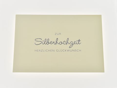 Hochzeitskarte mit silberner Schrift auf strukturiertem Papier, elegant gestaltet, hergestellt von Juwelier Harnisch, ideal für Glückwünsche zur Silberhochzeit.