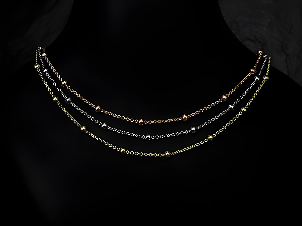Silber Kette Rundanker Kugelkette tricolor rhodiniert 90 cm von Juwelier Harnisch mit verschiedenen glänzenden Kugeln in gold, silber und rose auf einem dunklen Hintergrund.