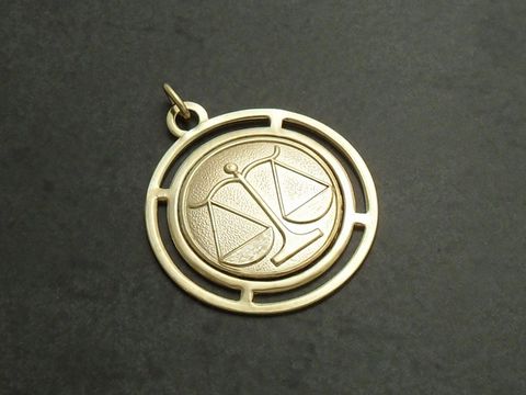 Goldfarbene, runde 3D-Platte mit dem Sternzeichen Waage, gefertigt von Juwelier Harnisch. Die Plakette zeigt eine stilisierte Waage in einem detailreichen Design.