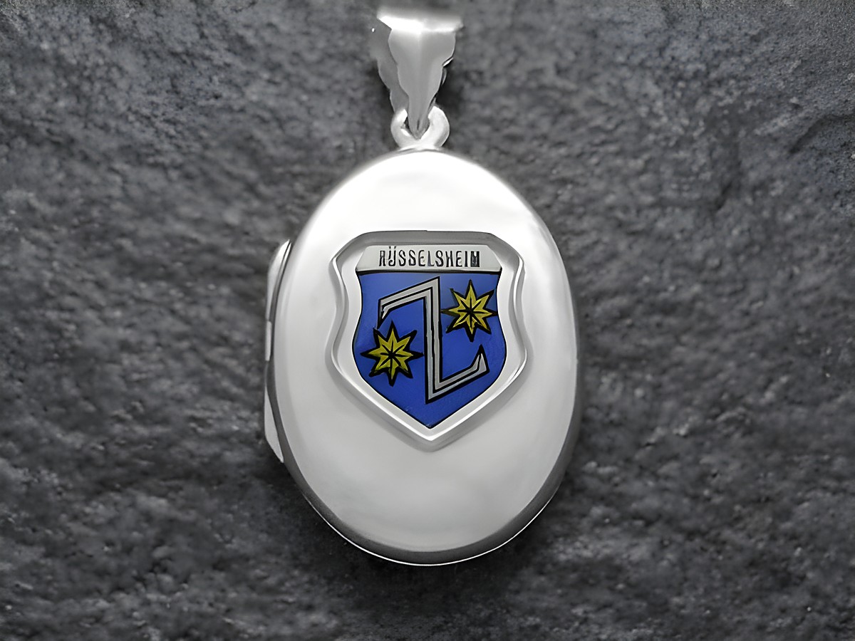 Das Bild zeigt ein silbernes Medaillon mit dem Wappen von Rüsselheim, das in Blau und Gelb gestaltet ist. Der Hersteller des Medaillons ist Juwelier Harnisch aus Hessen.