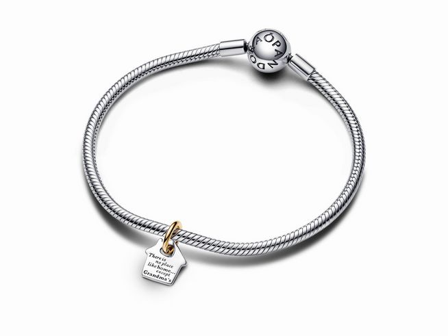 Pandora 763205C00 Bicolor Omas Haus Charm-Anhänger aus Silber und Gelbgold Vergoldung an einem flexiblen, silbernen Armband mit einem glänzenden Pandora Logo.