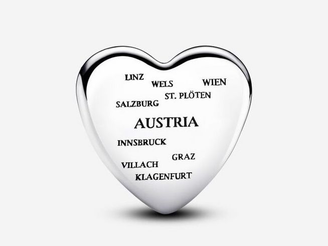 Herzförmiger Charm aus Silber mit eingravierten Städtenamen Österreichs, darunter Wien, Salzburg und Innsbruck, perfekt für eine edle Schmuckkollektion.