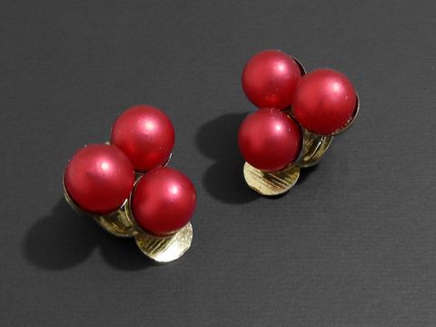 Modeschmuck Ohrclip elegant rot matt Zuchtperlenimitation von Juwelier Harnisch, mit zwei Gruppen aus jeweils zwei roten, matten Perlen und goldfarbener Klemmbasis.