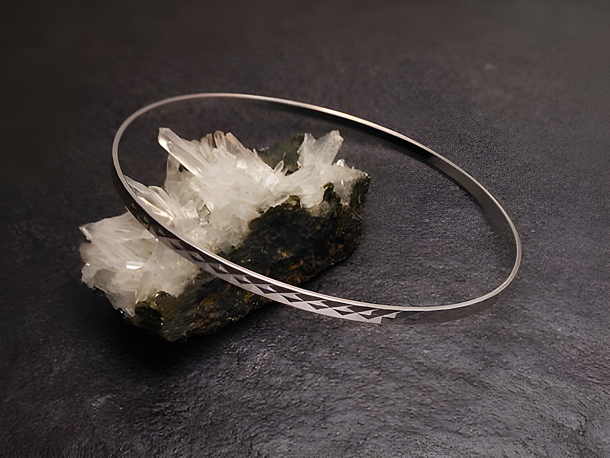 Armreifen fein - 2,5 mm - Weißgold 585 - 22 cm, Hersteller: Juwelier Harnisch, Armreifen auf einem dunklen Untergrund mit Kristallstücken im Hintergrund.