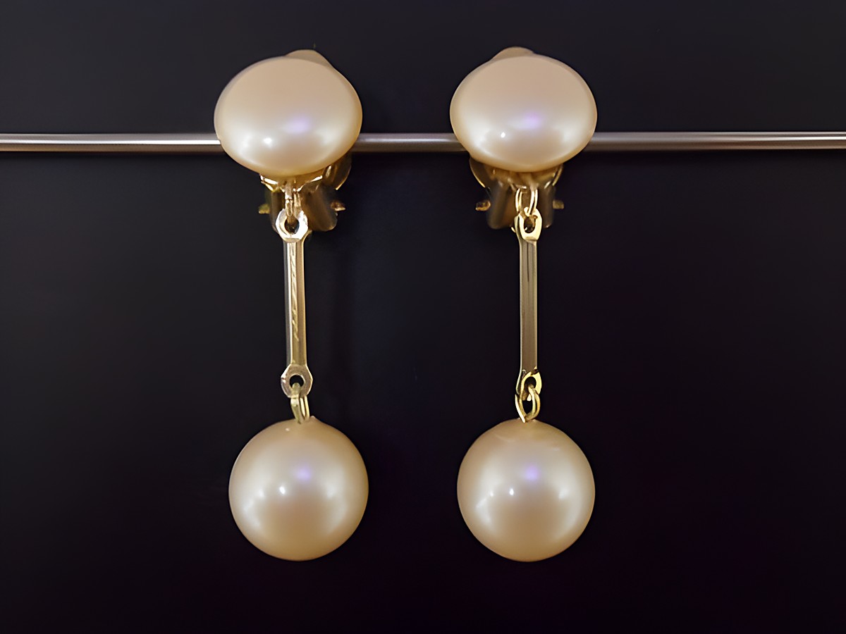 Ohrclip in hellrosa mit zeitlosem Design und goldfarbener Fassung, ergänzt durch eine synthetische Zuchtperle, hergestellt von Juwelier Harnisch.