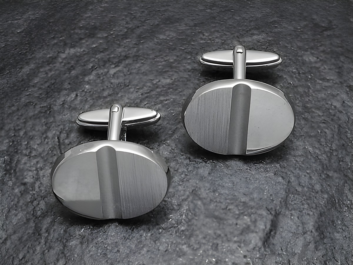 Manschettenknöpfe Silber im Modell Digital-Cut von Juwelier Harnisch aus echtem Silber, elegant und modern mit strukturiertem Design in ovaler Form, auf einem dunklen Untergrund platziert.