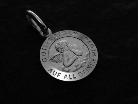 Ein silberner Anhänger in Form eines Engels mit der Inschrift Gottes Segen wende dich auf all deinen Wegen, gestaltet von Juwelier Harnisch, der Raphael Schutzengel darstellt.