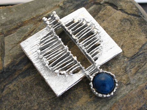 Silber Anhänger Design mit Sodalith aus echt Silber, hergestellt von Juwelier Harnisch, zeichnet sich durch ein besonderes Design aus und ist auf einem steinernen Untergrund abgebildet.