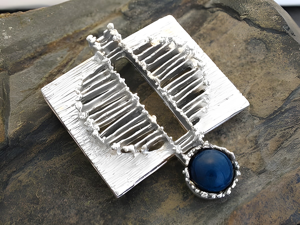 Silber Anhänger Design mit Sodalith aus echt Silber, hergestellt von Juwelier Harnisch, zeichnet sich durch ein besonderes Design aus und ist auf einem steinernen Untergrund abgebildet.