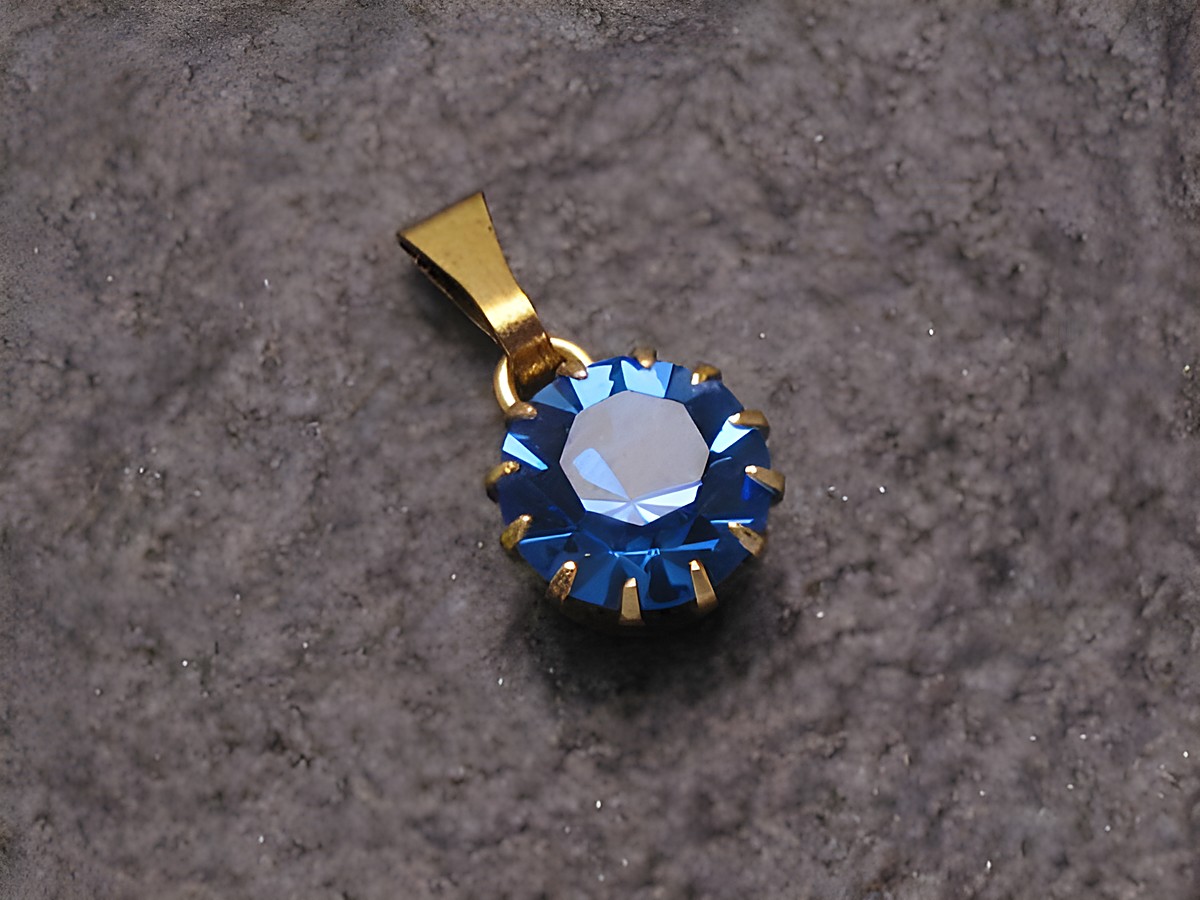 Blauer Strass Anhänger mit rundem Design, verziert mit funkelnden glitzernden Facetten, in goldfarbener Fassung, ideal für einen sexy Stadtlook, Hersteller: Juwelier Harnisch, auch in weiteren Formen erhältlich.