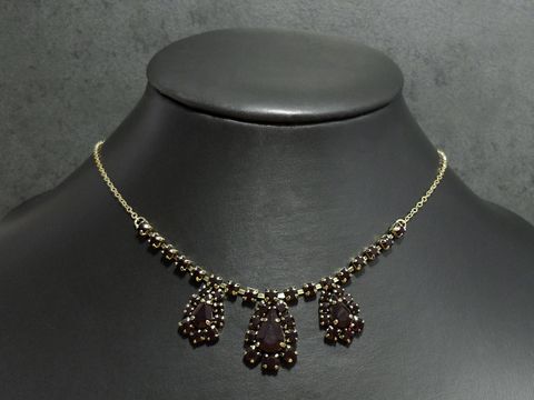 Elegante goldfarbene Halskette mit granatroten Anhängern, individuelle Länge von 42,5 bis 46,5 cm, von Juwelier Harnisch, ansprechende Fassung in Gold.