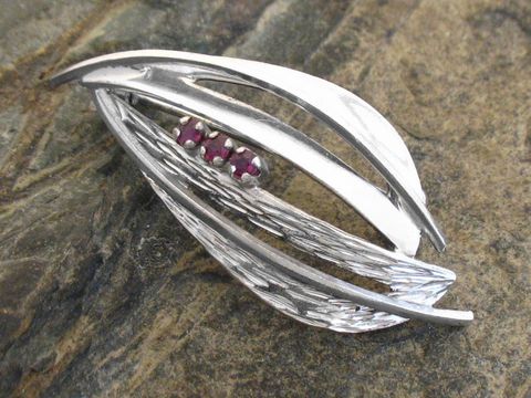 Brosche im Design mit Rubin aus Sterling Silber rhodiniert, von Juwelier Harnisch, mit eleganten geschwungenen Formen und drei rubinroten Steinen. Ideal für stilvolle Akzente.