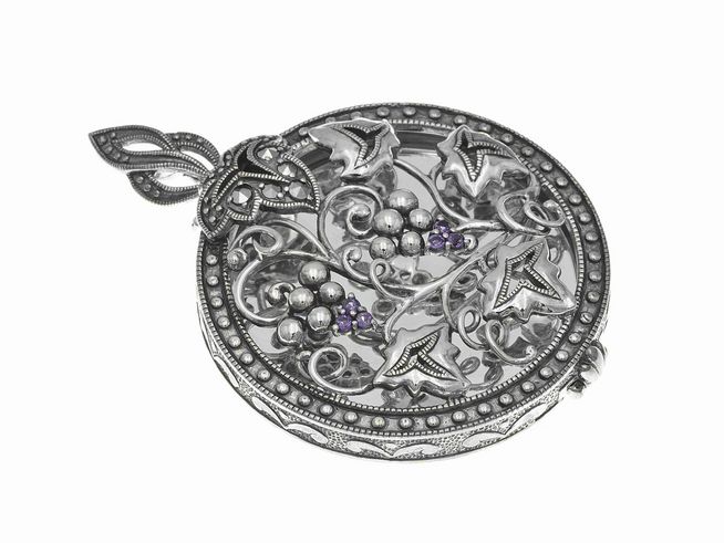 Ein nostalgisches Medaillon aus Sterling Silber mit filigranen Verzierungen, einschließlich Amethyststeinen, das elegant und zeitlos wirkt, hergestellt von Juwelier Harnisch.