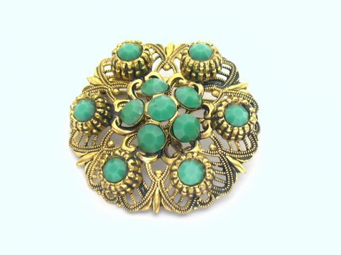 Brosche im Sexy City Look in smaragdgrün, rund mit filigranem Goldrahmen und mehreren türkisfarbenen Steinen, Hersteller: Juwelier Harnisch.