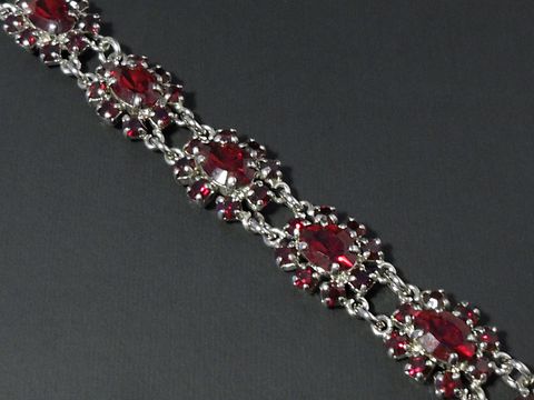 Strass Armband weiblich in rubinrot mit silberfarbenem Element, verziert mit ovalen Steinen. Längenverstellbar von 18,5 bis 21 cm. Hersteller Juwelier Harnisch.