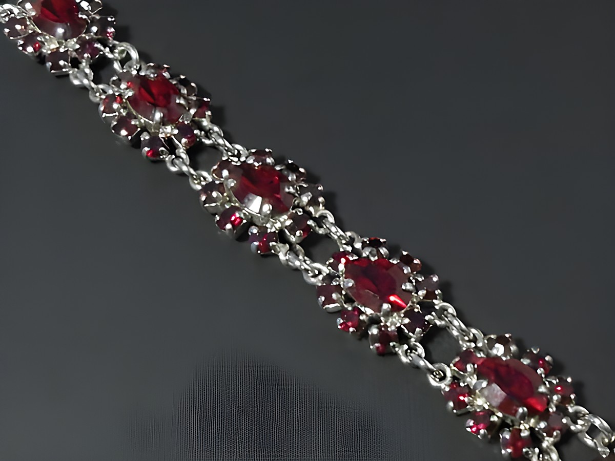 Strass Armband weiblich in rubinrot mit silberfarbenem Element, verziert mit ovalen Steinen. Längenverstellbar von 18,5 bis 21 cm. Hersteller Juwelier Harnisch.