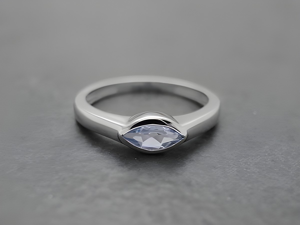 Ring aus rhodiniertem Sterling Silber mit einem blauen Topas in marquise Form, Größe 60, hergestellt von Juwelier Harnisch. Elegantes und zeitloses Schmuckstück für jeden Anlass.
