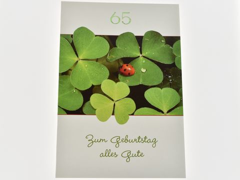 Geburtstagskarte mit Glücksklee und einem Marienkäfer, verdeutlicht mit der Aufschrift "Zum Geburtstag alles Gute" und der Zahl 65, hergestellt von Juwelier Harnisch.