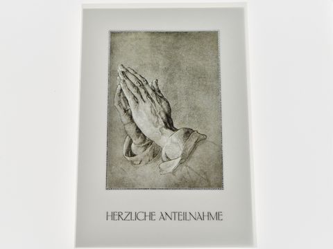 Das Bild zeigt betende Hände auf einem Trauerkarte-Design mit der Aufschrift "HERZLICHE ANTEILNAHME" am unteren Rand, hergestellt von Juwelier Harnisch.