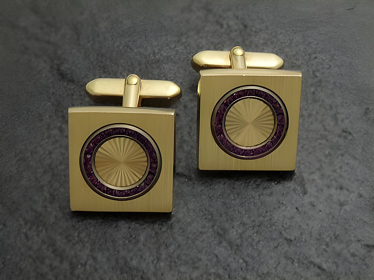 Manschettenknöpfe Funkel vergoldet mit lila Strass und quadratischer Form, Hersteller Juwelier Harnisch, goldfarbenes Design mit glänzender Oberfläche und lila Akzenten.