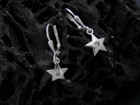 Zwei Ohrhänger aus Sterling Silber in Sternform mit Zirkonia-Steinen, hergestellt von Juwelier Harnisch, auf einer dunklen Oberfläche präsentiert.