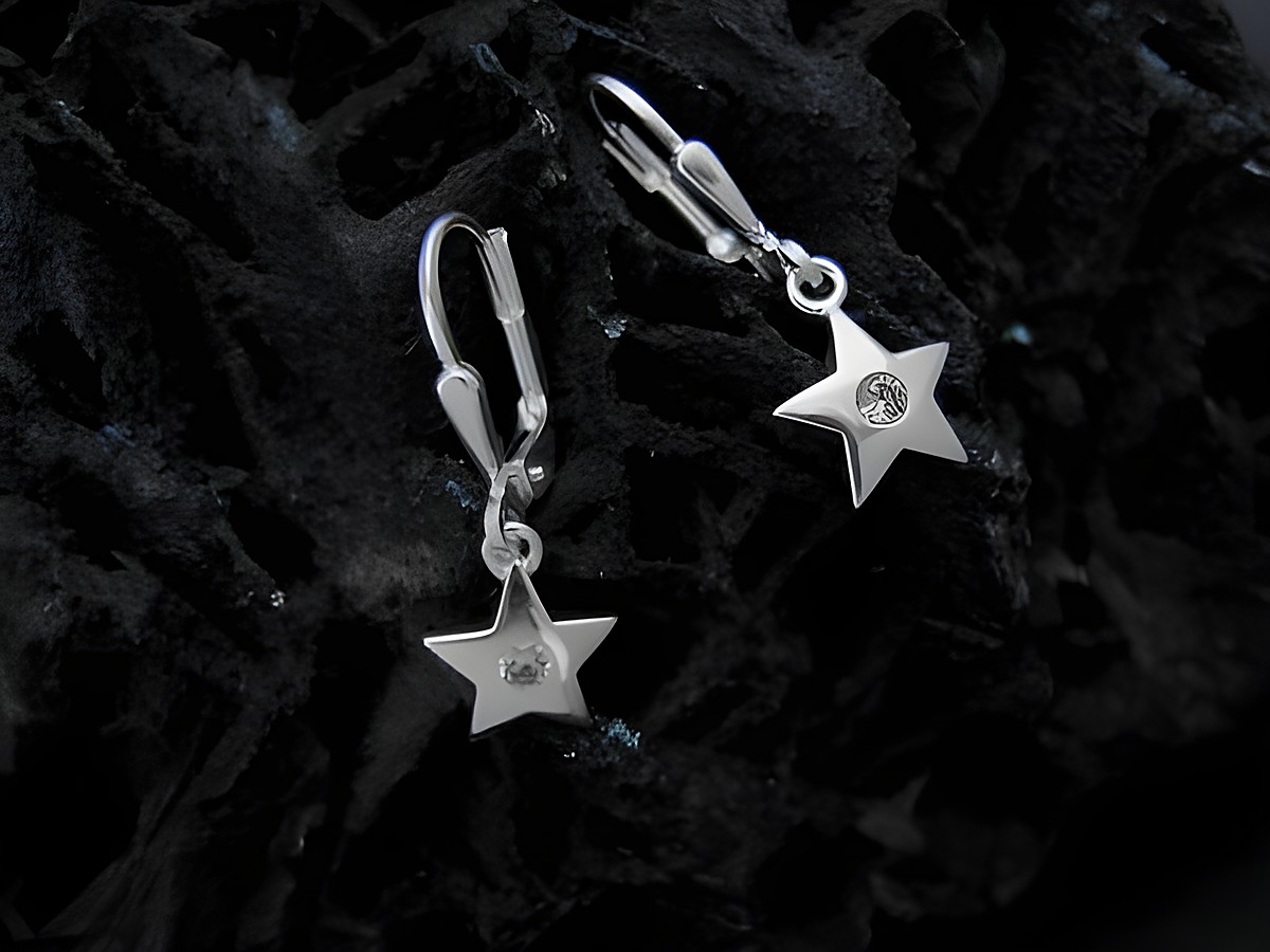 Zwei Ohrhänger aus Sterling Silber in Sternform mit Zirkonia-Steinen, hergestellt von Juwelier Harnisch, auf einer dunklen Oberfläche präsentiert.