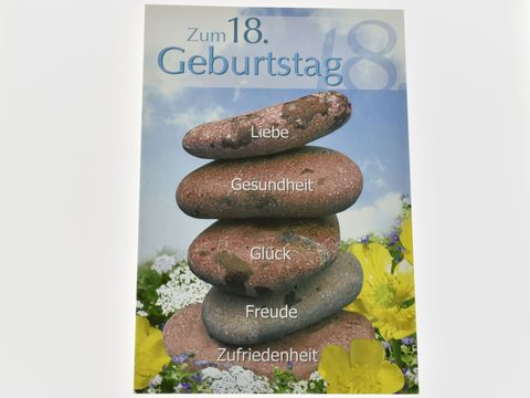 Eine Geburtstagskarte zum 18. Geburtstag mit einem bunten Hintergrund und gestapelten Steinen, auf denen die Worte Liebe, Gesundheit, Glück, Freude und Zufriedenheit geschrieben stehen. Hersteller: Juwelier Harnisch.