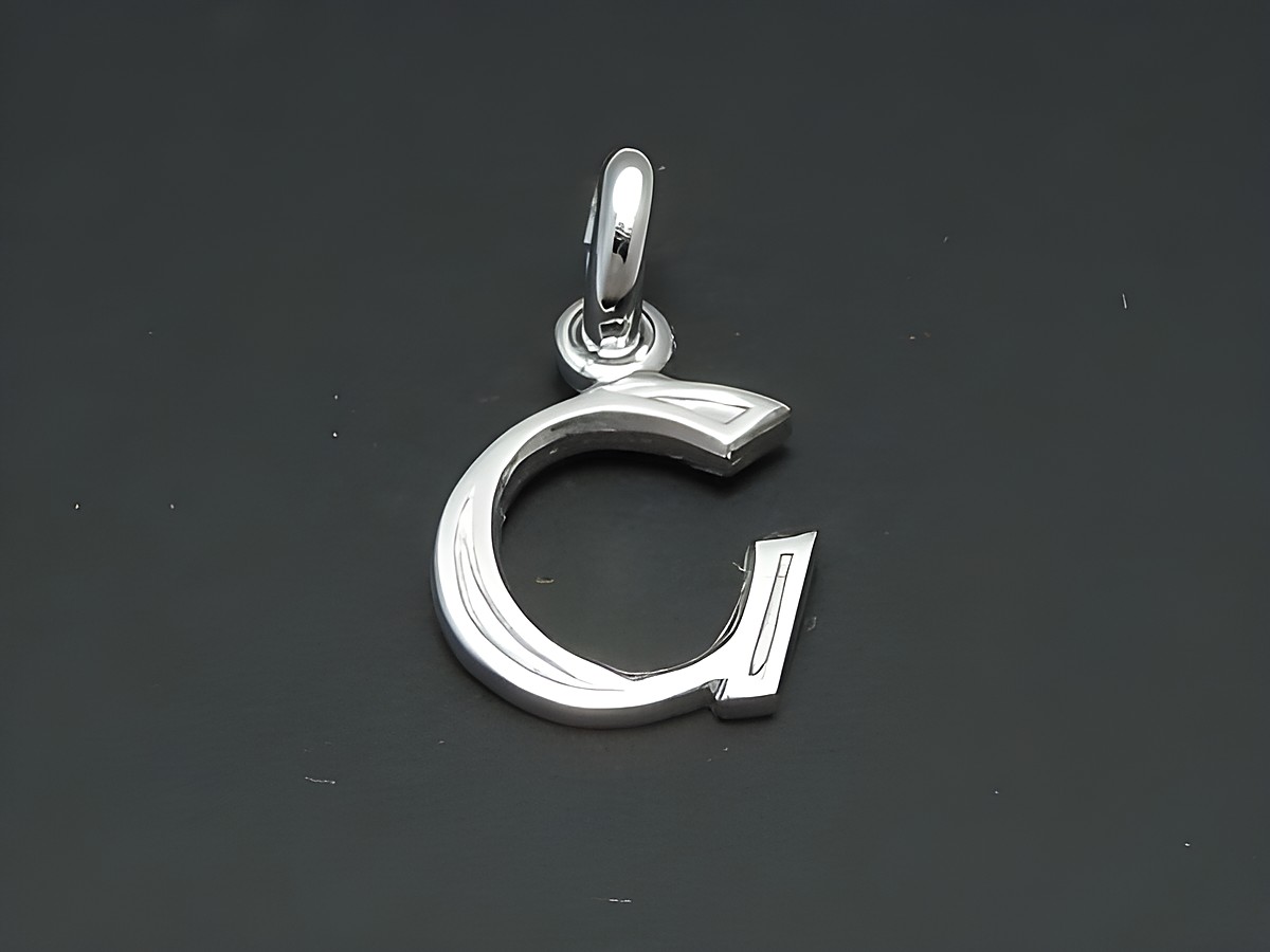 Buchstabe G Anhänger aus rhodiniertem Silber mit geschwungener Form, hergestellt von Juwelier Harnisch. Ideal als persönliches Schmuckstück oder Geschenk.