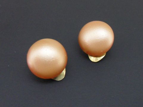 Dunkelapricotfarbene Ohrclips in zeitlosem Design mit goldfarbener Fassung und seidenmatter synthetischer Zuchtperle von Juwelier Harnisch.