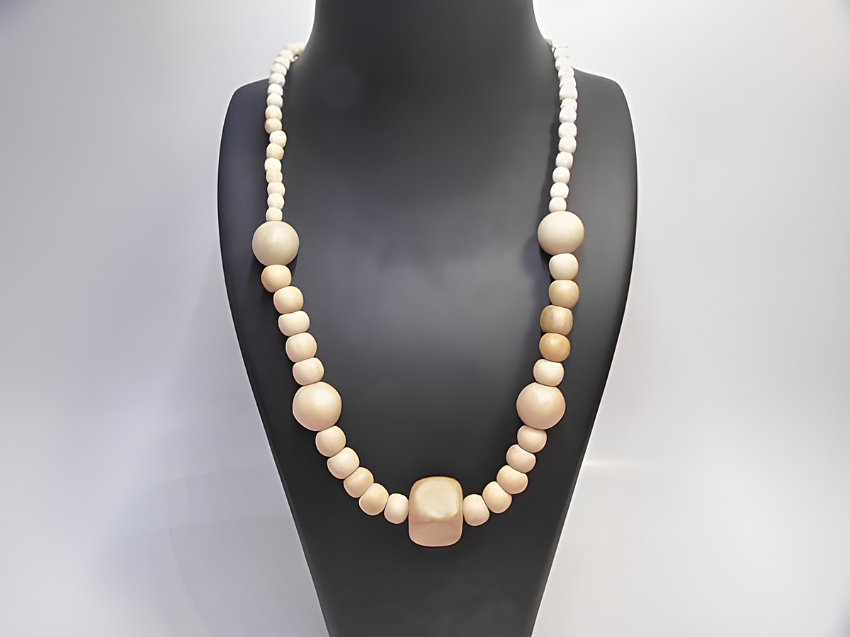 Holzkette aus naturbraunen Holzperlen in verschiedenen Größen, 18 mm dick, 60 cm lang, gefertigt vom Juwelier Harnisch, präsentiert auf einem schwarzen Schmuckständer.