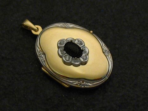 Medaillon Cabochon Gold 333 bicolor von Juwelier Harnisch, zarter ovaler Anhänger mit glänzender goldener Oberfläche und einem zentralen schwarzen Element, kunstvolle Details und edle Verarbeitung.