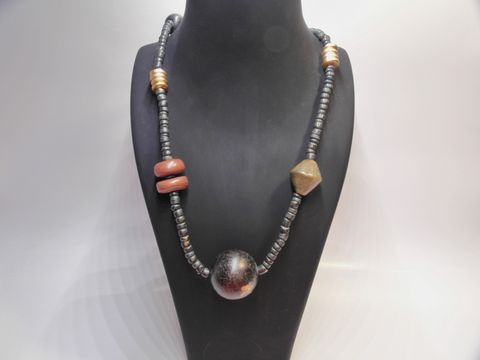 Bunte Holzkette Multiform 28 mm 90 cm von Juwelier Harnisch, bestehend aus verschiedenen Holzperlen in unterschiedlichen Formen und Farben, präsentiert auf einem Schmuckständer.