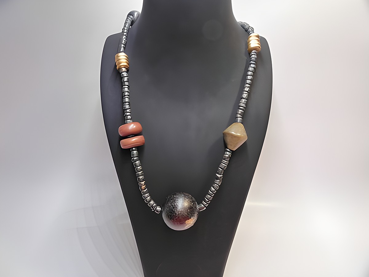 Bunte Holzkette Multiform 28 mm 90 cm von Juwelier Harnisch, bestehend aus verschiedenen Holzperlen in unterschiedlichen Formen und Farben, präsentiert auf einem Schmuckständer.