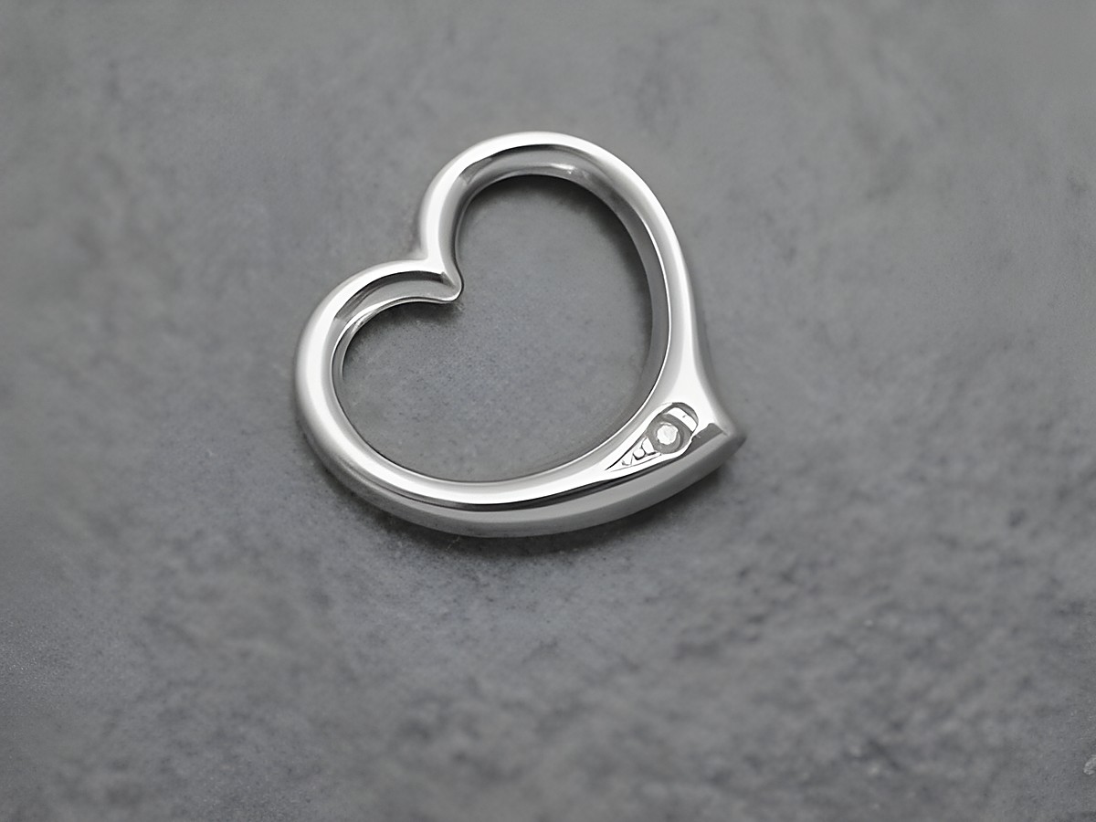 Herzanhänger aus rhodiniertem Sterling Silber mit durchlaufendem Design und einem Diamanten. Hersteller Juwelier Harnisch, schlichter und eleganter Schmuck für jeden Anlass.