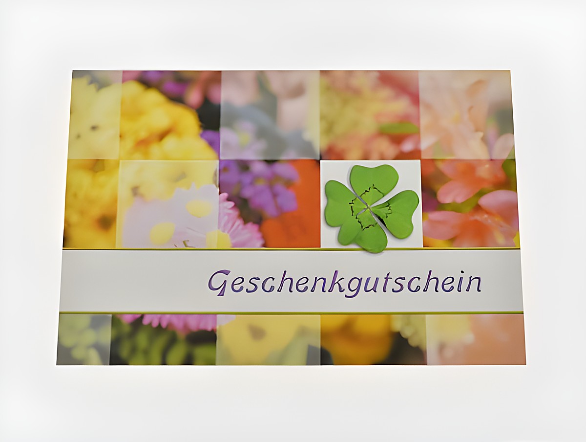 Gutscheinkarte mit einem Kleeblatt auf einem bunten Blumenhintergrund, beschriftet mit Gutschein, Hersteller Juwelier Harnisch.