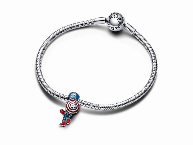 Das Bild zeigt ein Silberarmband von Pandora mit einem charm in Form von Captain America, verziert mit blauen Zirkonia und dem charakteristischen Schild in rot, weiß und blau.