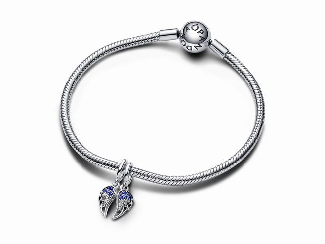 Ein eleganter Pandora Charm-Anhänger in Form von funkelnden Engelsflügeln, aus Sterling Silber mit buntem Steinmix in Blau, der an einem feinen Armband befestigt ist.