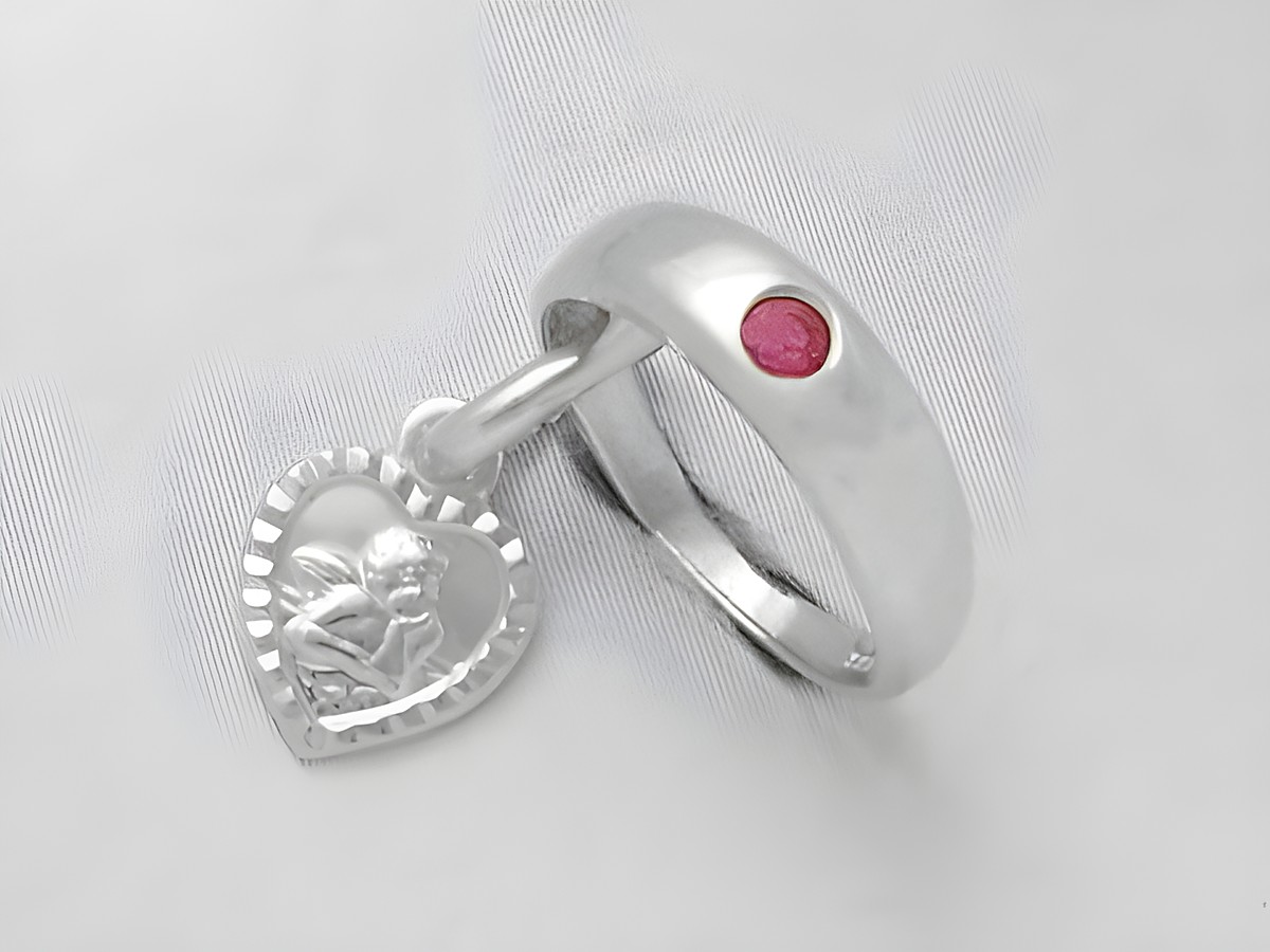 Taufring aus 925 Silber mit einem Herzanhänger und Schutzengel, verziert mit einem Rubin, Hersteller Juwelier Harnisch, elegantes Design für besondere Anlässe.
