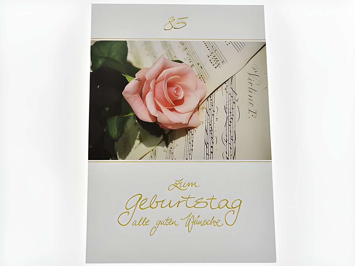Geburtstagskarte mit einer rosafarbenen Rose auf Notenpapier, beschriftet mit den Worten Zum Geburtstag und alten guten Wünschen, Hersteller Juwelier Harnisch, passend für Jubiläen.