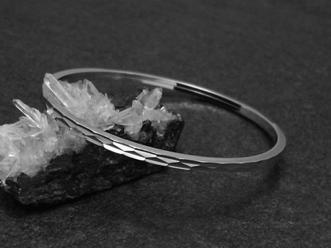 Silber Armreifen - zeitlos - 3 mm - rhodiniert - 18 cm vom Hersteller Juwelier Harnisch, schön präsentiert auf einer schwarzen Fläche mit Kristallen im Hintergrund.