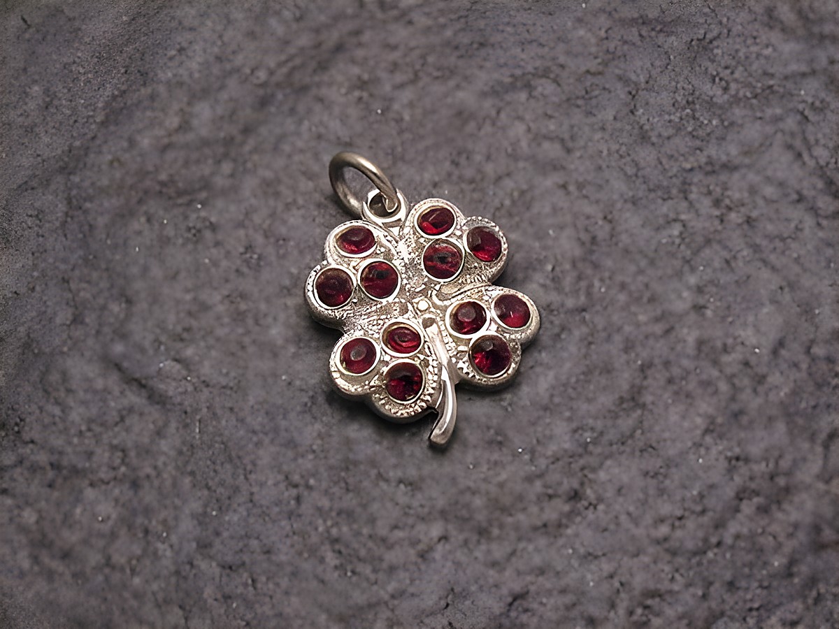 Roter Strass Anhänger in Kleeblattform im Sexy City Look, hergestellt von Juwelier Harnisch, funkelnde rot-glänzende Steine in silberfarbener Fassung, ideal als modisches Accessoire.