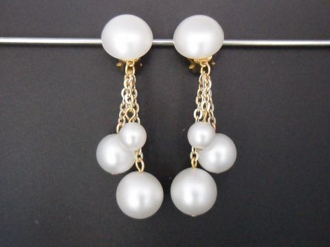 Zeitlose Ohrclips aus perlweißem Kunstharz und goldfarbenen Details, mit mehreren hängenden Perlen, Hersteller Juwelier Harnisch. Elegantes Accessoire für besondere Anlässe.
