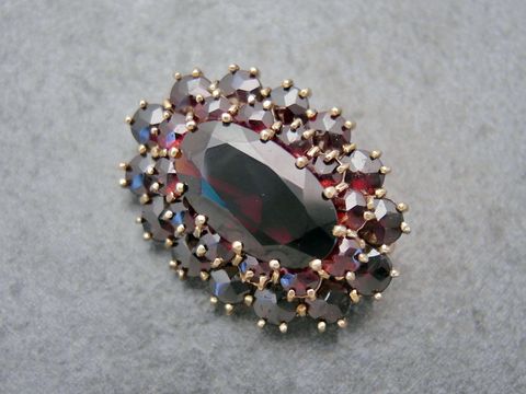 Granat Schmuck Brosche 29,2 mm oval in Gold mit funkelnden Granatsteinen, designet vom Juwelier Harnisch, elegante und zeitlose Brosche für jeden Anlass.