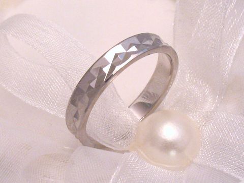 400386-0 Trauring Ehering FANTASTIC aus Weißgold 333 in Größe 54/17,2, hergestellt von Juwelier Harnisch, mit einer facettierten Oberfläche und elegantem Design, auf einer weißen Schleife und einer Perle arrangiert.