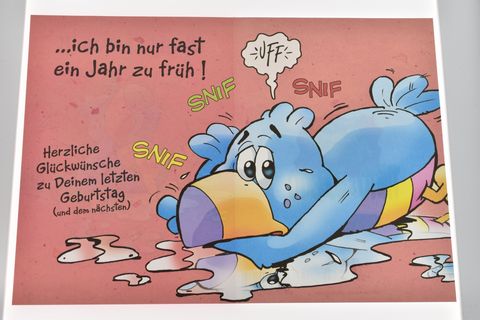 Eine Geburtstagskarte mit einem weinenden Vogel auf pinkem Hintergrund. Der Vogel wirkt traurig und hat Text, der humorvoll auf den verpassten Geburtstag hinweist. Hersteller: Juwelier Harnisch.