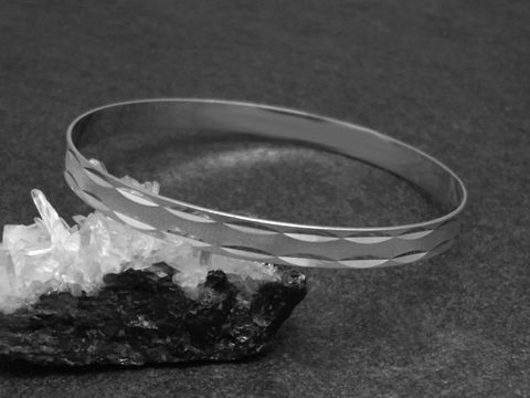 Silber Armreifen gestrichelt 6,4 mm rhodiniert 20,5 cm von Juwelier Harnisch auf schwarzem Hintergrund, elegant und zeitlos, ideal für jeden Anlass.
